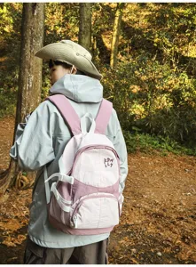 Vista dettagliata dell'elegante zaino da esterno rosa e bianco in una scena forestale.