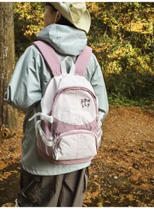 Vista dettagliata dello zaino da esterno rosa e bianco in un ambiente forestale naturale.