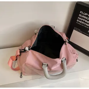 Pink fitness duffel bag detail showcasing spacious interior, sturdy grey handles and shoulder strap.