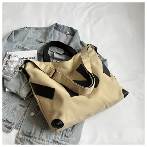 Canvas tote bag detail view showing durable beige fabric, black leather patch and straps.