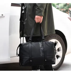 Close-up detail of black travel duffel bag with vertical lettering and sturdy handles.