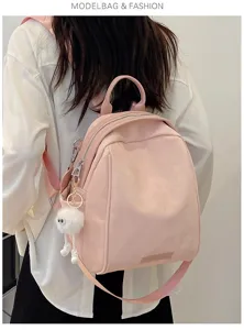 Pink casual backpack for women, stylish commuting daypack with cute fluffy charm detail.