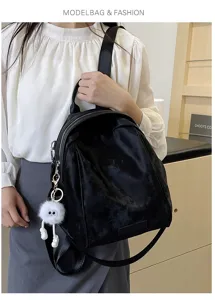 Detail shot of a stylish black women backpack featuring a cute fluffy eye charm and sleek design.