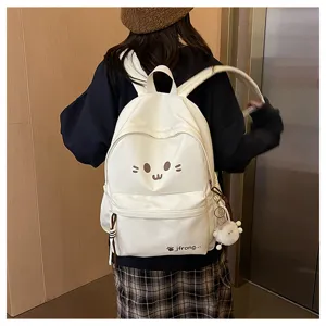 Detail view of the cute white cartoon backpack worn outdoors, showing cute face and mini plush pendant.