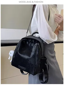 Detailed view of women's black casual backpack with soft texture and cute fluffy pendant.