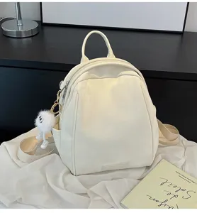 Detailed view of white minimalist casual backpack with cute fluffy keychain and straps.