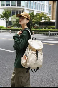 Detailed view of casual lightweight outdoor backpack in beige, featuring practical drawstring and flap.