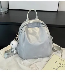 Detailed view of a trendy silver metallic women backpack with cute furry pendant and straps.