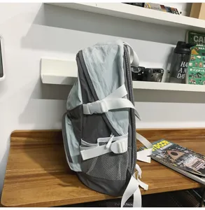Vista dettagliata laterale dello zaino in nylon grigio leggero con cinghie bianche e tasca in rete.