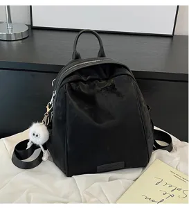 Black women backpack detail view, casual commuting school bag with furry charm pendant and zipper.