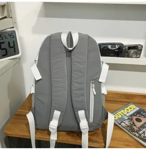 Zaino casual grigio in tessuto con spallacci bianchi e tasche laterali per outdoor.