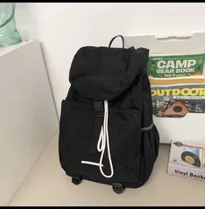 Detailed view of black travel backpack with white drawstring and buckle closure for outdoor.