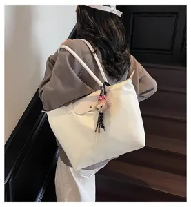 Detailansicht einer lässigen weißen Shopper Tasche auf Schulter mit Anhänger auf Treppe.