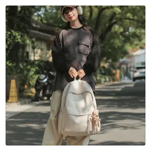 Detailansicht des lässigen minimalistischen beigen Rucksacks mit Fronttasche und Bärenanhänger.