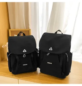 Details of the trendy black canvas backpack featuring flap top, drawstring, and front pocket.