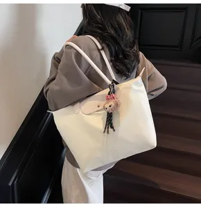 Detailansicht der großen beigen Tasche mit Lederklappe und süßem Plüschanhänger für Damen.
