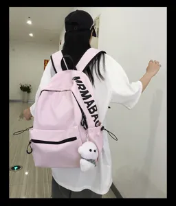 Pink canvas backpack for women, casual school bookbag with cute plush pendant and large capacity.