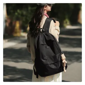 Außendetailansicht eines einfachen schwarzen Studentenrucksacks mit Fronttasche und Bär.