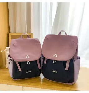 Color-block detail view of two stylish backpacks on wooden desk with clean white curtains.