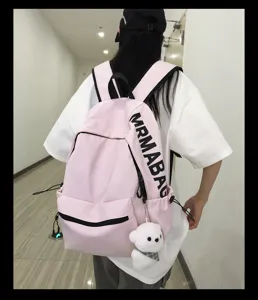 Pink canvas backpack detail showing cute bear pendant and side pockets for school use.