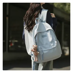 Detailansicht eines minimalistischen hellblauen Studentenrucksacks mit Bärenanhänger.