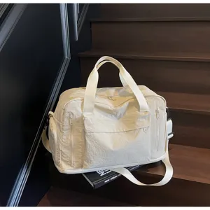 Detailed view of large capacity beige travel duffel bag with multiple zipper pockets on stairs.