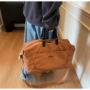 Large capacity travel duffel bag detail, showing durable brown fabric, shoulder strap and sturdy handles.
