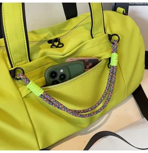 Fluorescent green gym duffel bag with colorful rope handle and front pocket detail.