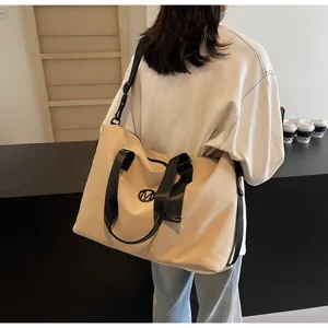 Detailed view of the large capacity beige canvas travel duffel bag with black straps and logo.