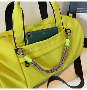 Neon green gym bag detail showing front pocket, black handles and colorful braided strap.