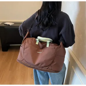 Detailed view of the large brown travel duffel bag featuring stylish green handles and straps.