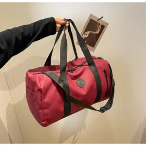 Detail view of large capacity waterproof travel duffel bag in burgundy with shoulder strap.