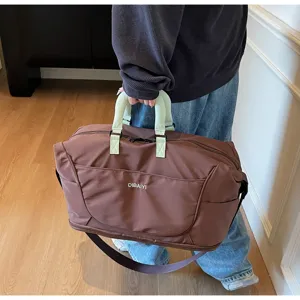 Detailed view of the large capacity brown travel duffel bag featuring contrast green handles.