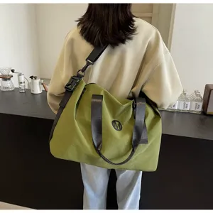 Detailed view of large capacity green canvas travel shoulder bag with durable straps.
