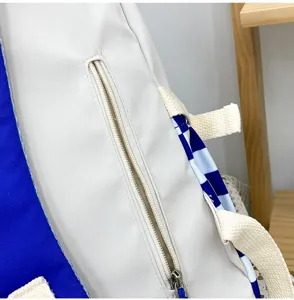 Dettaglio ravvicinato dello zaino in tela bicolore con tasca con cerniera e fodera blu.