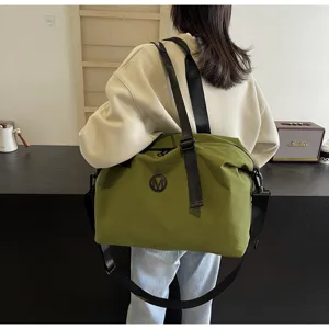 Detailed shot of the green travel duffel bag with black straps worn by a model in a setting.