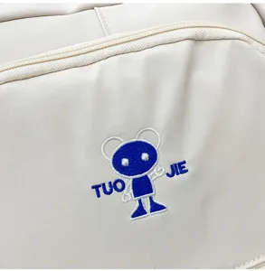 Primo piano dettagliato di uno zaino in tela beige con logo ricamato di cartone.