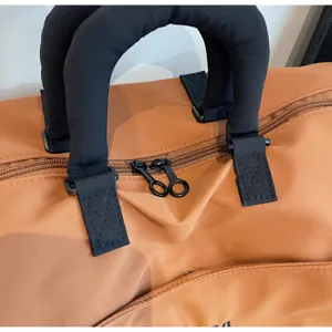 Close-up detail of travel duffel bag handle zipper, premium brown fabric durable luggage.