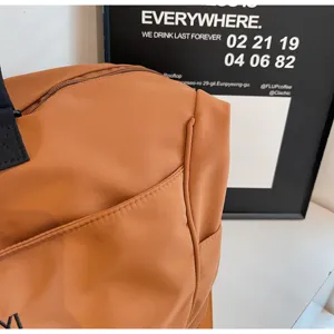 Brown travel duffel bag detail shot, showing durable fabric texture and handle strap.