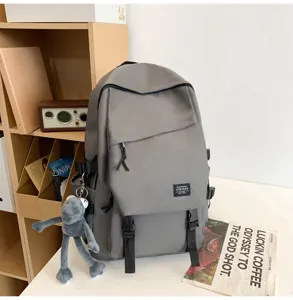 Detailansicht des grauen Freizeitrucksacks mit mehreren Taschen und Plüschanhänger im Zimmer.