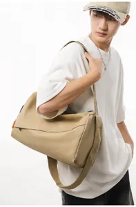 Detail view of the khaki lightweight sports duffel bag worn by model, showing waterproof fabric.