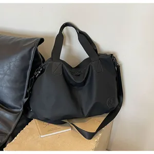 Black nylon tote bag detail showing large capacity, durable fabric and wide shoulder strap.