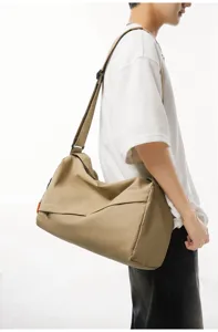 Detailed view of the casual khaki crossbody sports duffel bag worn by a model in studio.