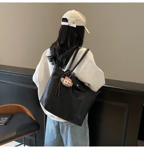 Detailansicht einer stilvollen schwarzen Schultertasche mit niedlichem Anhänger für den Alltag.