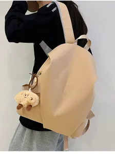 Vista dettagliata dello zaino beige minimalista ed elegante con grazioso ciondolo in peluche.