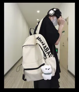 Korean style campus student solid color casual canvas backpack with cute bear pendant detail.