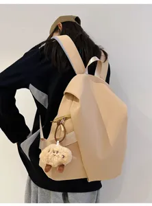Vista dettagliata del elegante zaino beige minimalista con grazioso ciondolo in peluche per uso quotidiano.