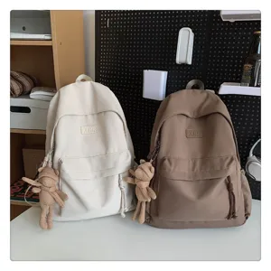 Minimalistischer Canvas Schulrucksack Detailansicht mit Bärenanhänger und zwei Farboptionen.