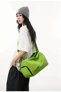 Detailed view of the green waterproof gym duffel bag with strap, worn by a model.