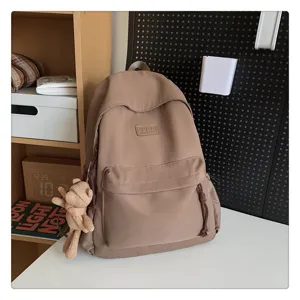 Einfacher einfarbiger khaki Rucksack Detailansicht mit süßem Bärenanhänger und Vordertasche.
